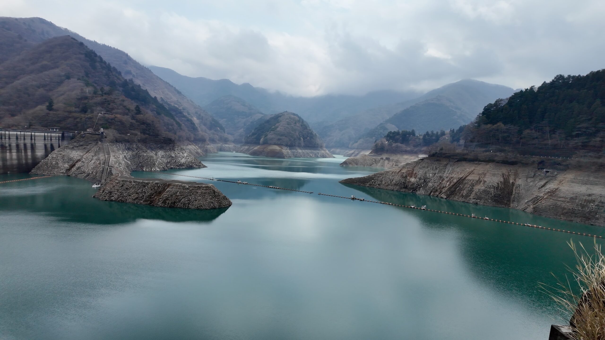 水位が大幅に低下し法面が白く露出した奥多摩湖の風景